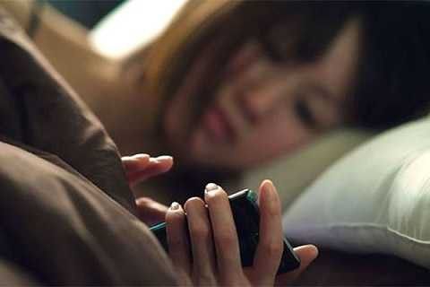 Sử dụng điện thoại trước khi đi ngủ trong ánh sáng yếu rất nguy hại sức khỏe. Ảnh minh họa